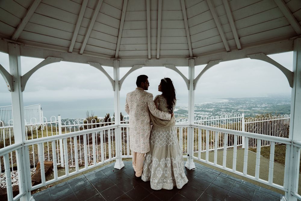 Panoramic view of an arched white gazebo walkway with metal railings and cityscape vistas below.