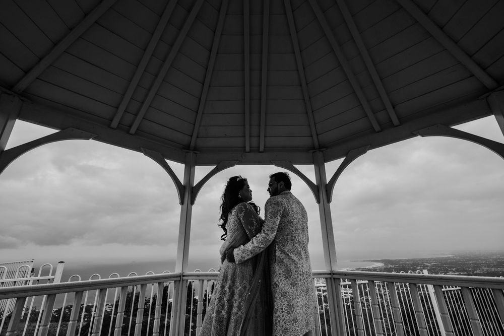 Black and white panoramic view through a covered gazebo overlooking a coastal landscape.
