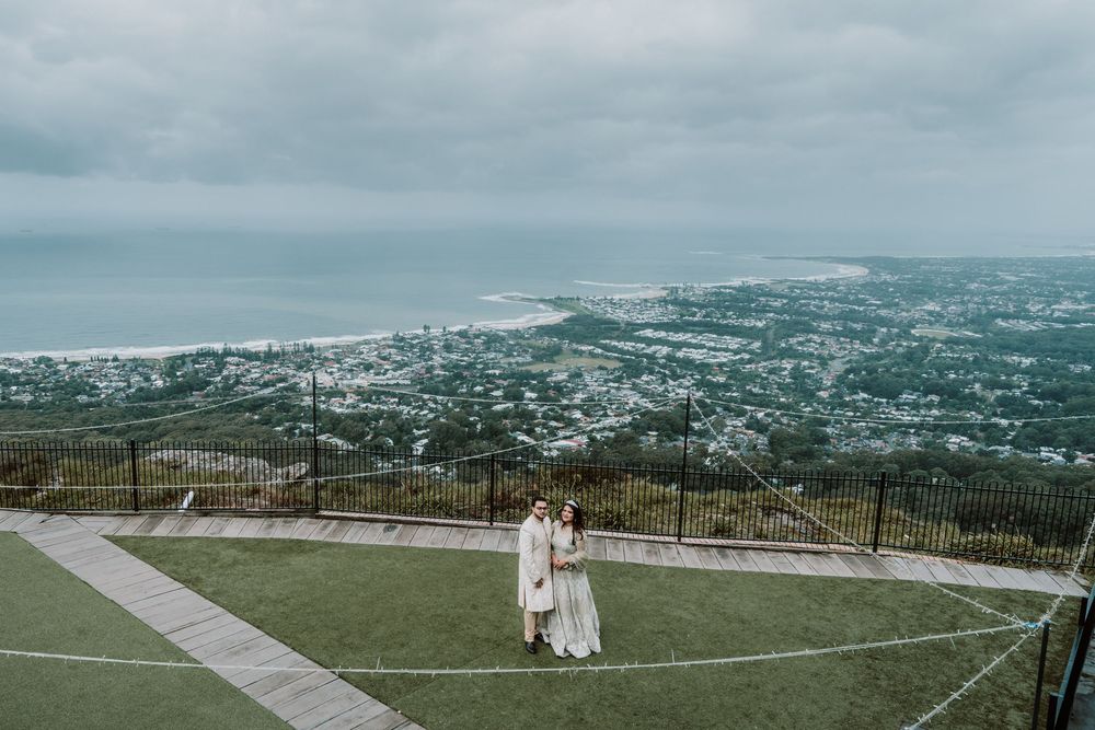 Wide panoramic view of a seaside city from a hilltop observation point with green lawns in the foreground.