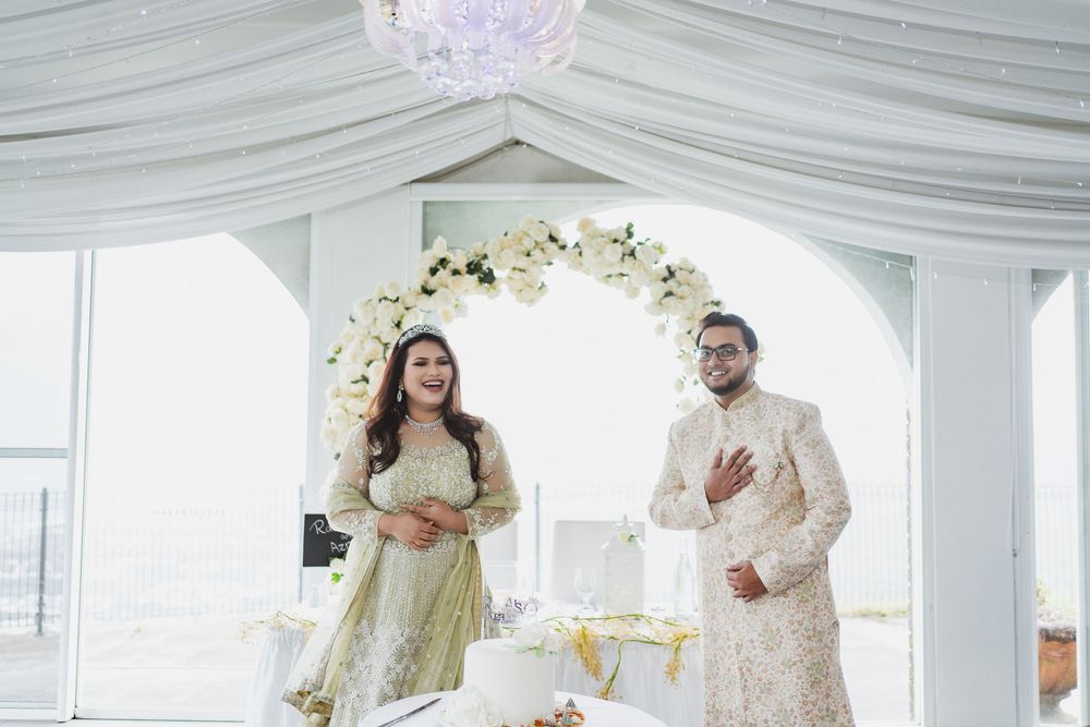 Newlyweds celebrate under a white draped canopy decorated with crystal chandelier and floral arrangements.