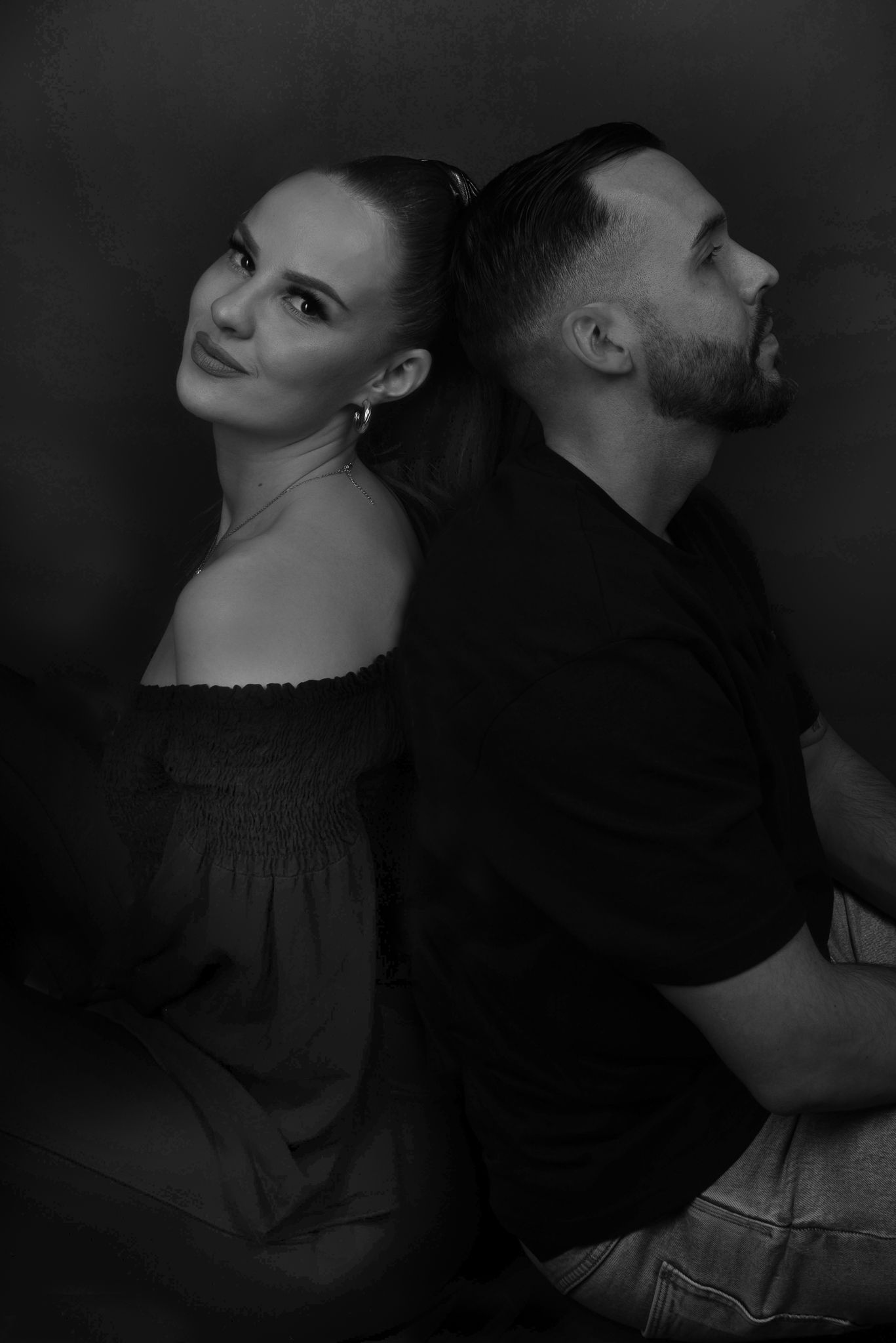 Love Story Fotografie, Stylish couple in black clothing pose back-to-back in moody black and white portrait.