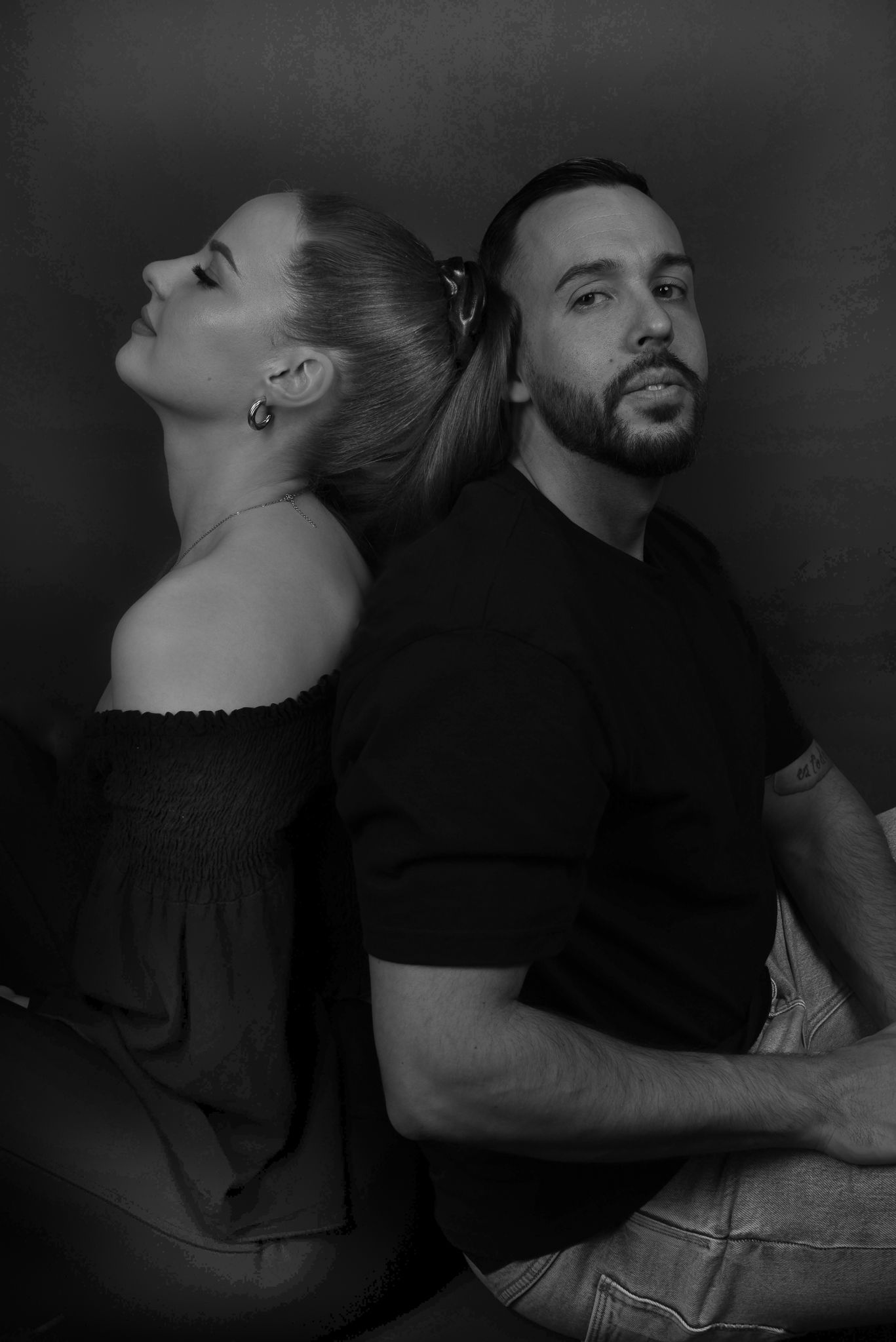 Love Story Fotografie, Artistic black and white portrait of couple in black clothing posed back to back.