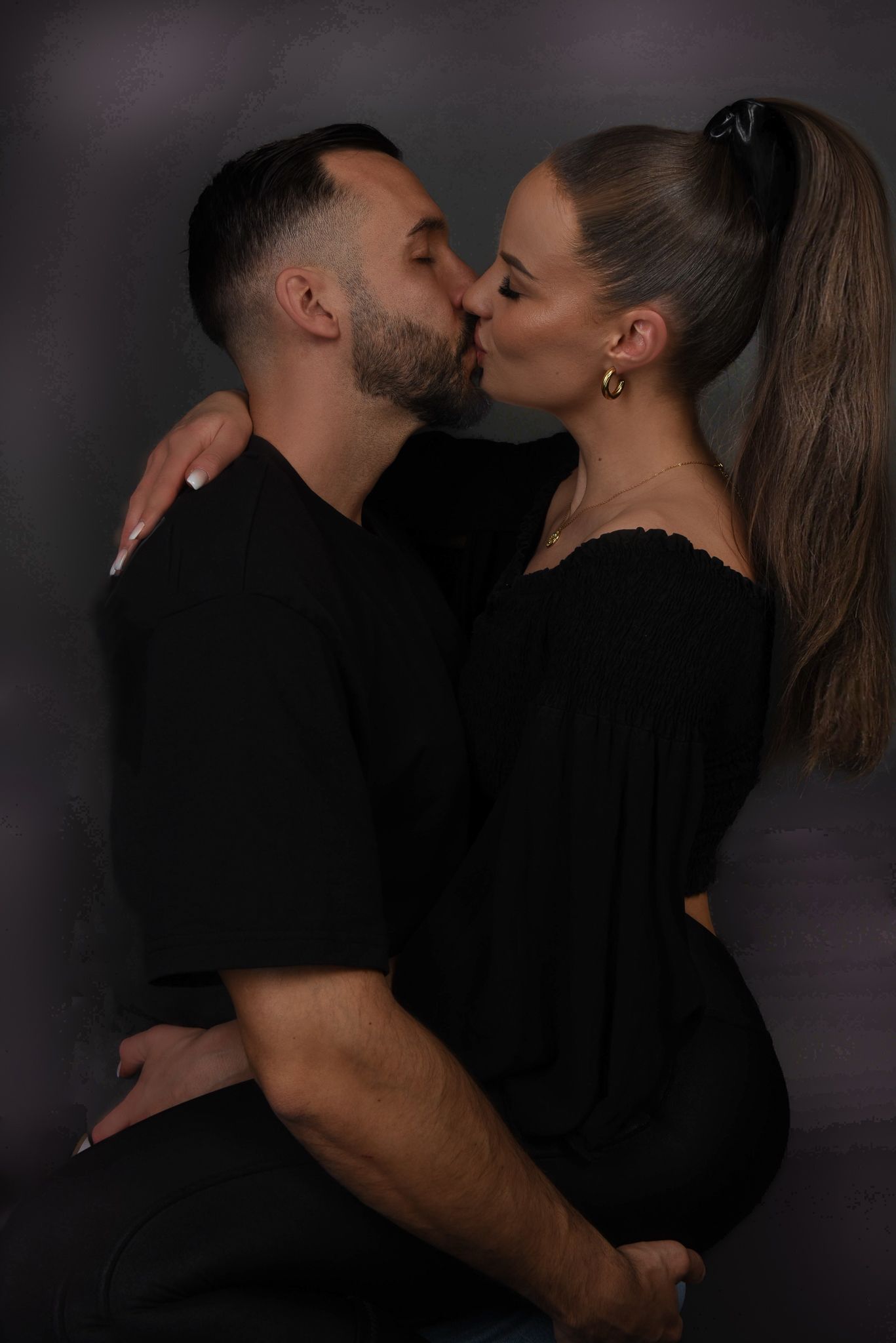 Love Story Fotografie, Intimate black and white photo of a couple in dark clothing sharing a passionate kiss.