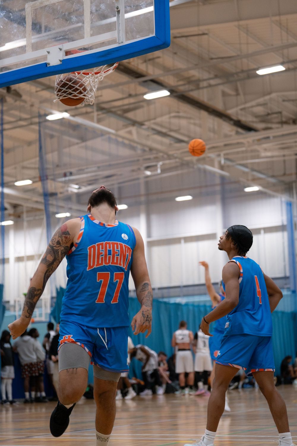 Basketball players in blue jerseys competing during indoor game.