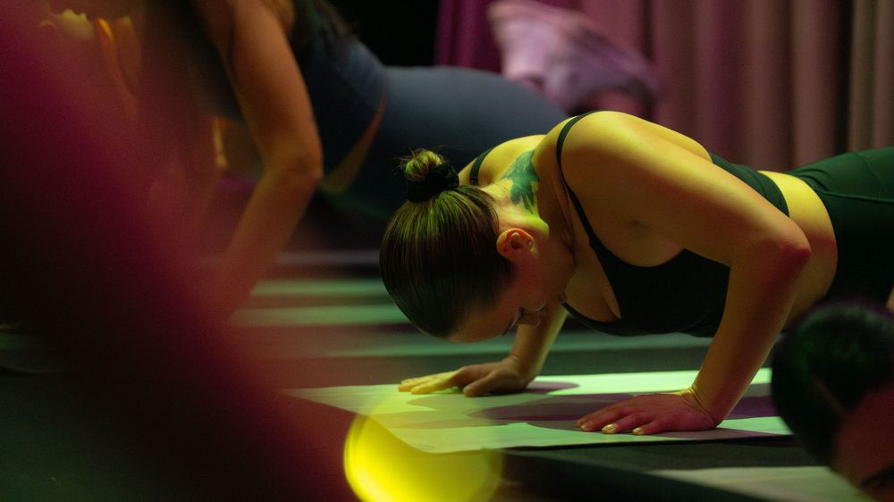 A person doing pushups in a dark room with green lighting.