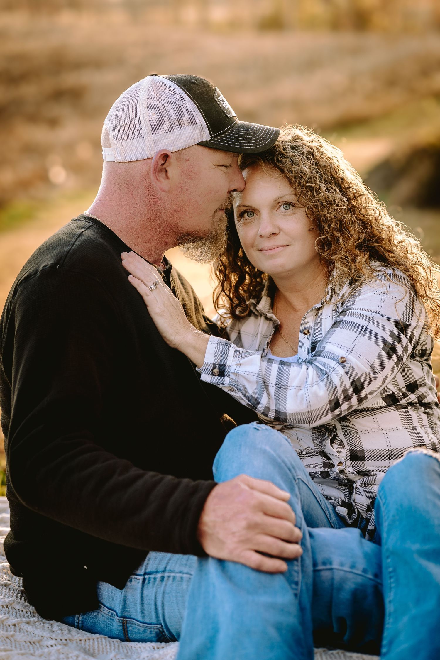 Intimate couple in casual wear sharing tender moment outdoors at sunset.