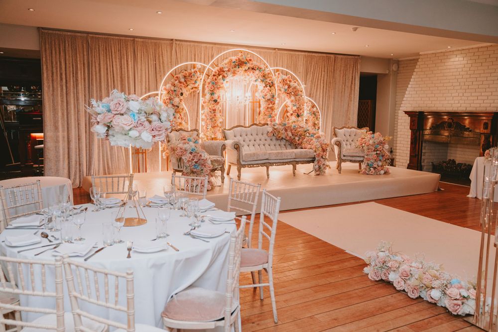 Wedding reception venue with gold arch backdrop and white table settings.