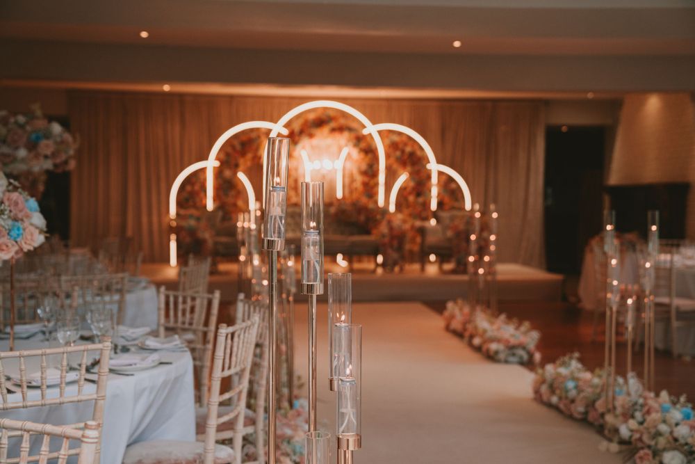 Wedding venue with crystal chandeliers and gold arch backdrop illuminated in warm lighting.