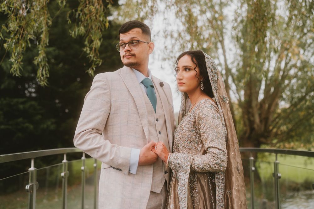 Wedding portrait of couple in light-colored attire standing on outdoor terrace.