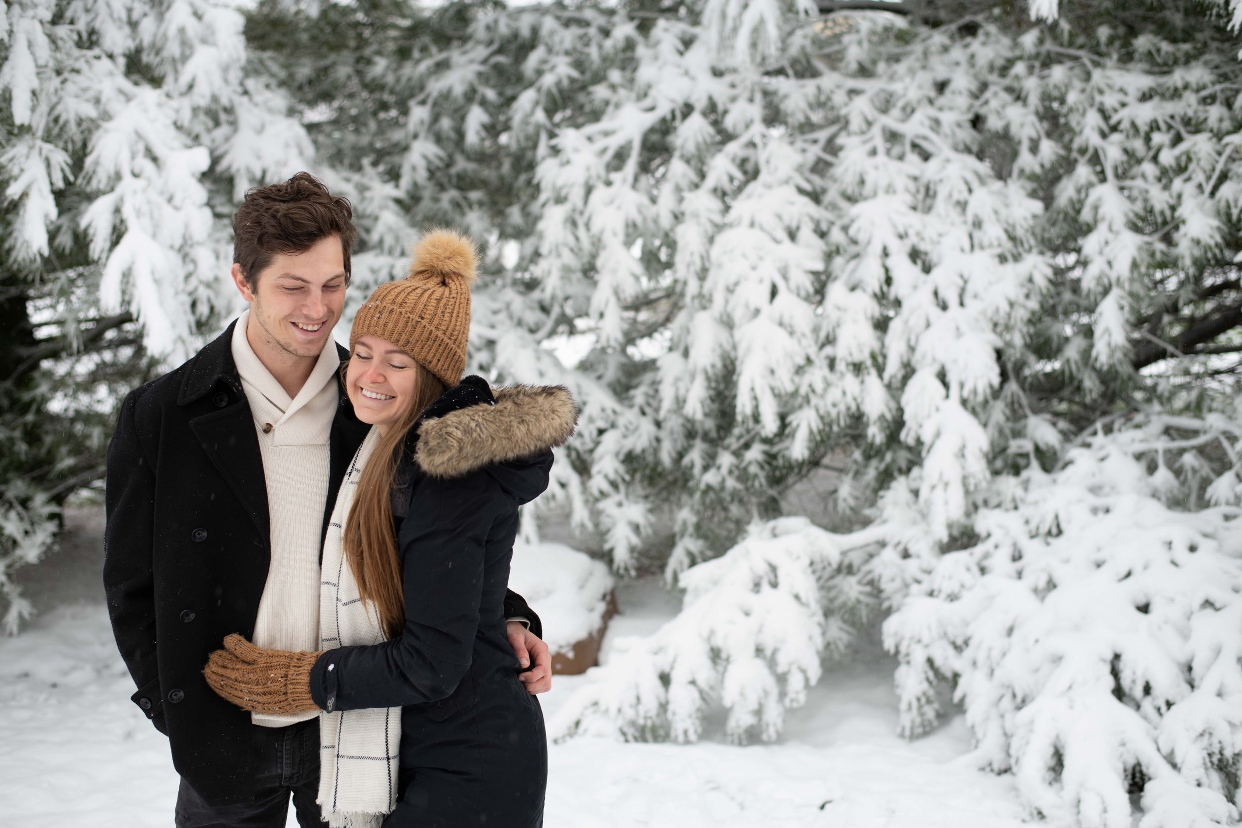 A loving winter moment captured between two people against a backdrop of snow-covered trees.