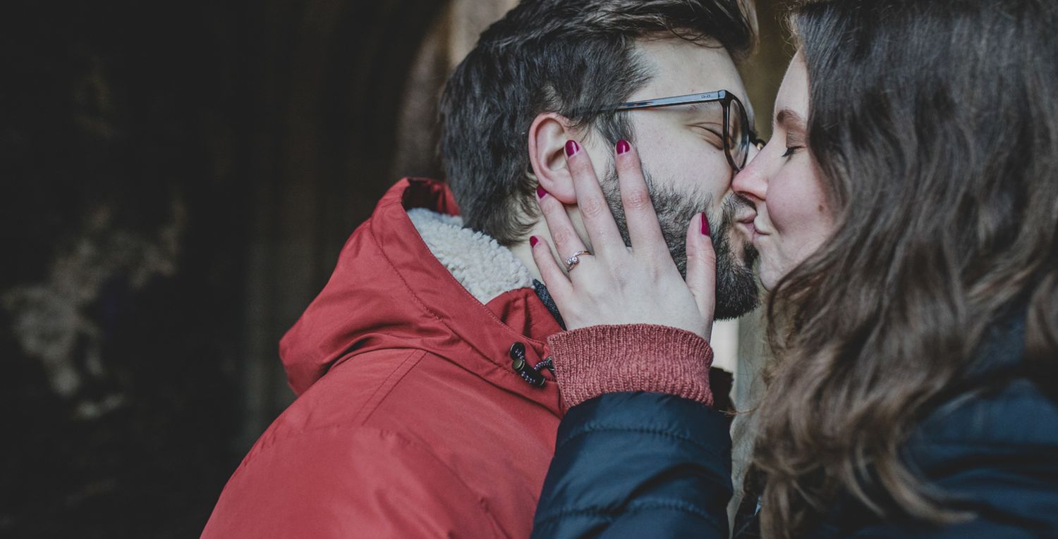A romantic outdoor kiss between two people wearing winter coats on a dark moody day.
