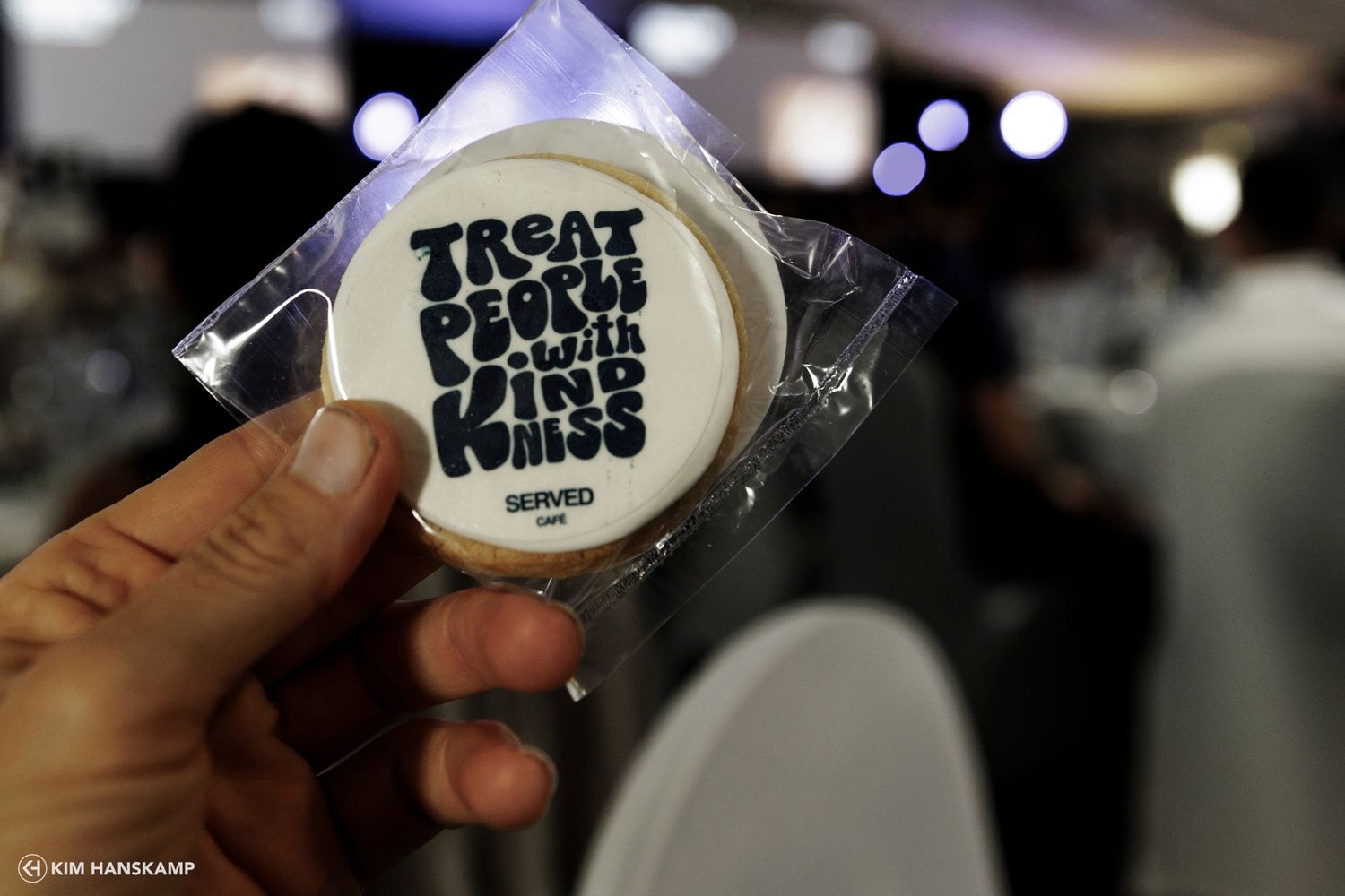 A close-up shot of someone holding a circular white event badge or sticker.