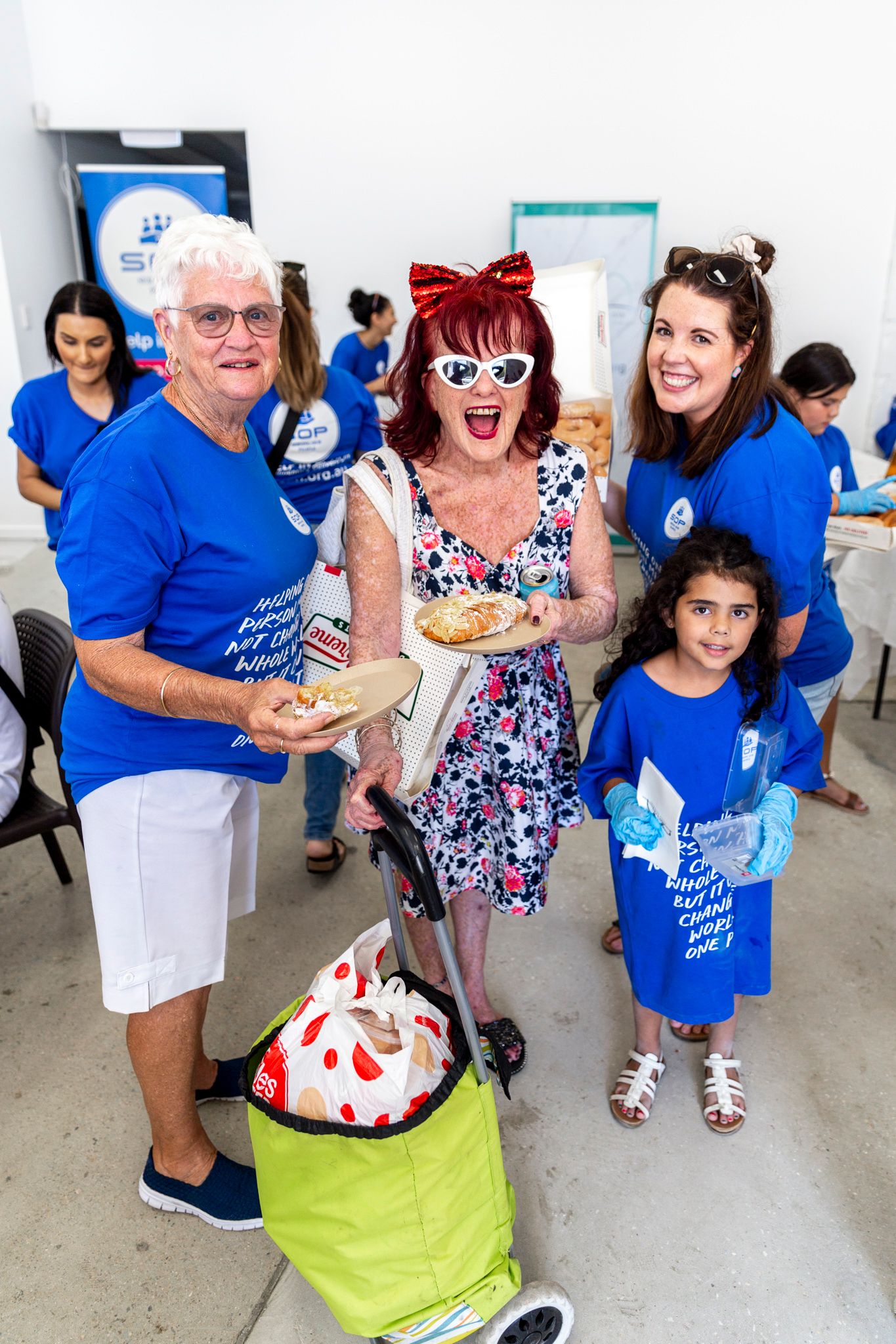 Group photo at a community event with people wearing blue shirts and one in a polka dot dress.