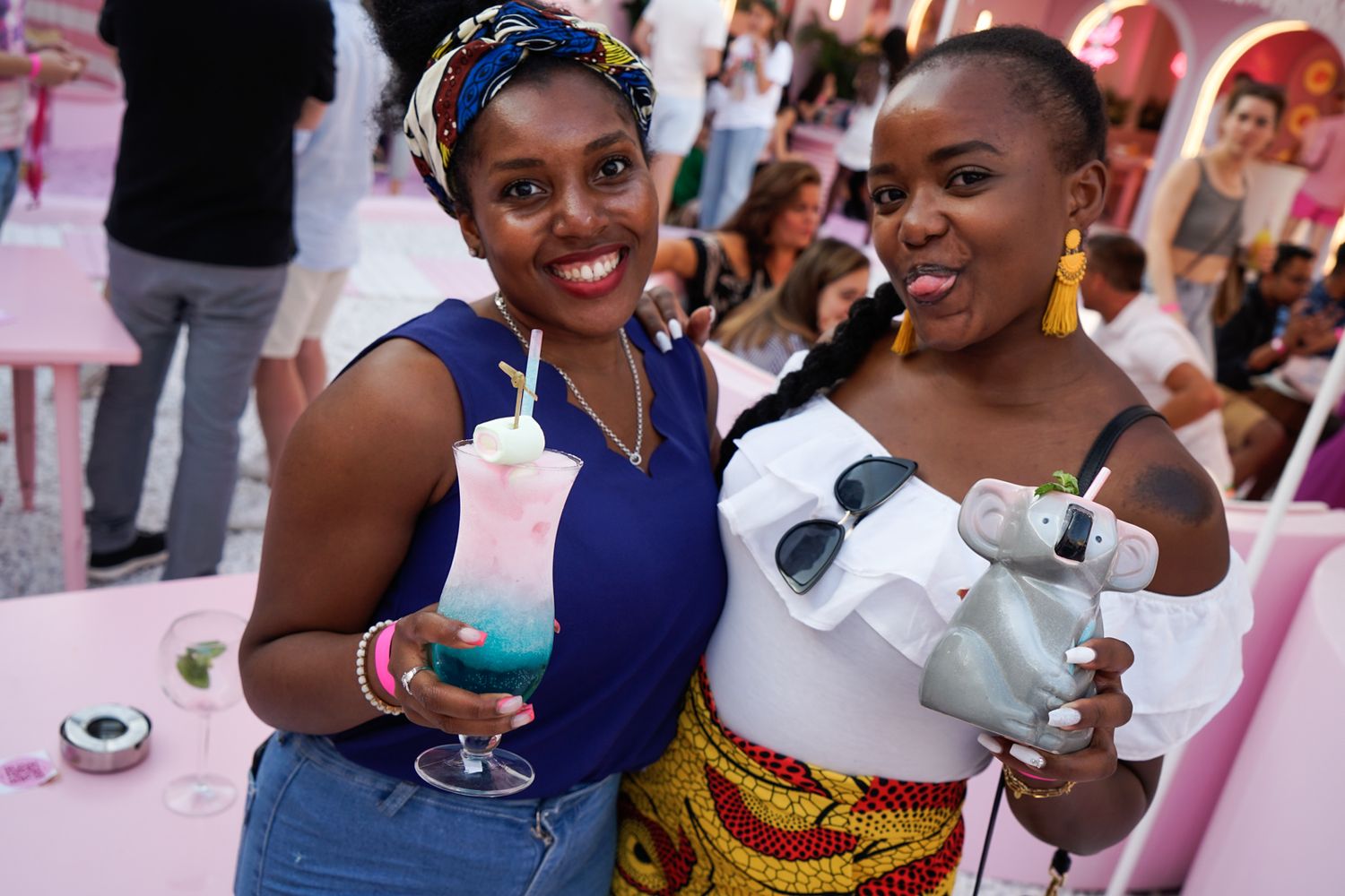 Friends enjoying colorful cocktails at pink-themed social event.