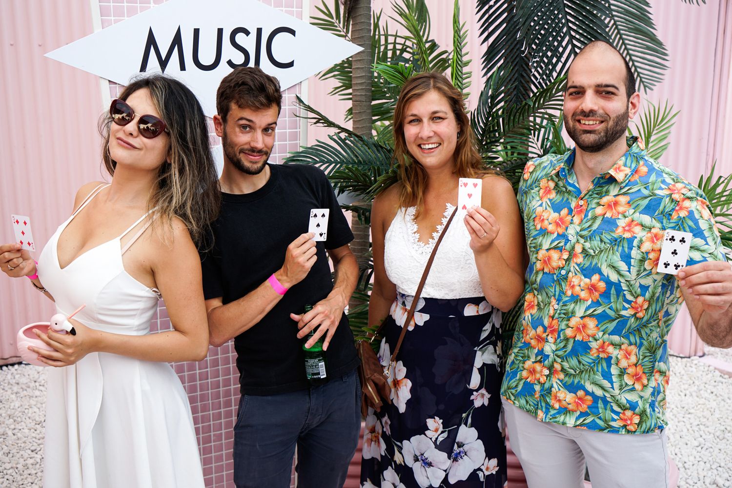Group of friends posing next to a pink wall with a music sign.