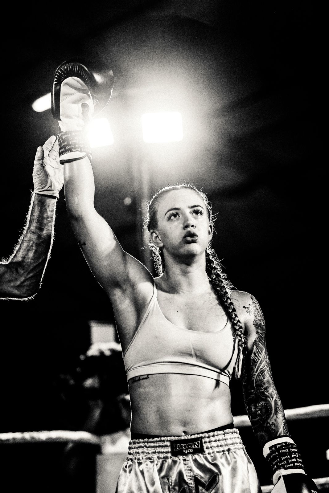 Black and white photo of a victorious boxer holding up a championship belt.