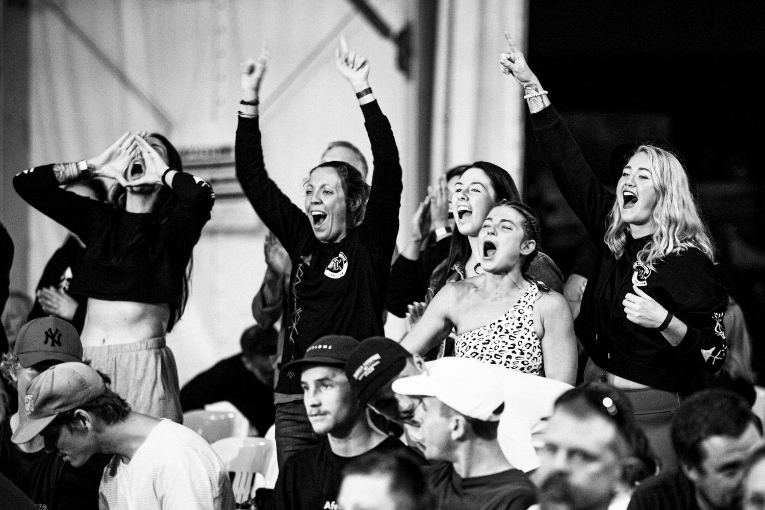Black and white photo of excited fans cheering at a concert or sports event.