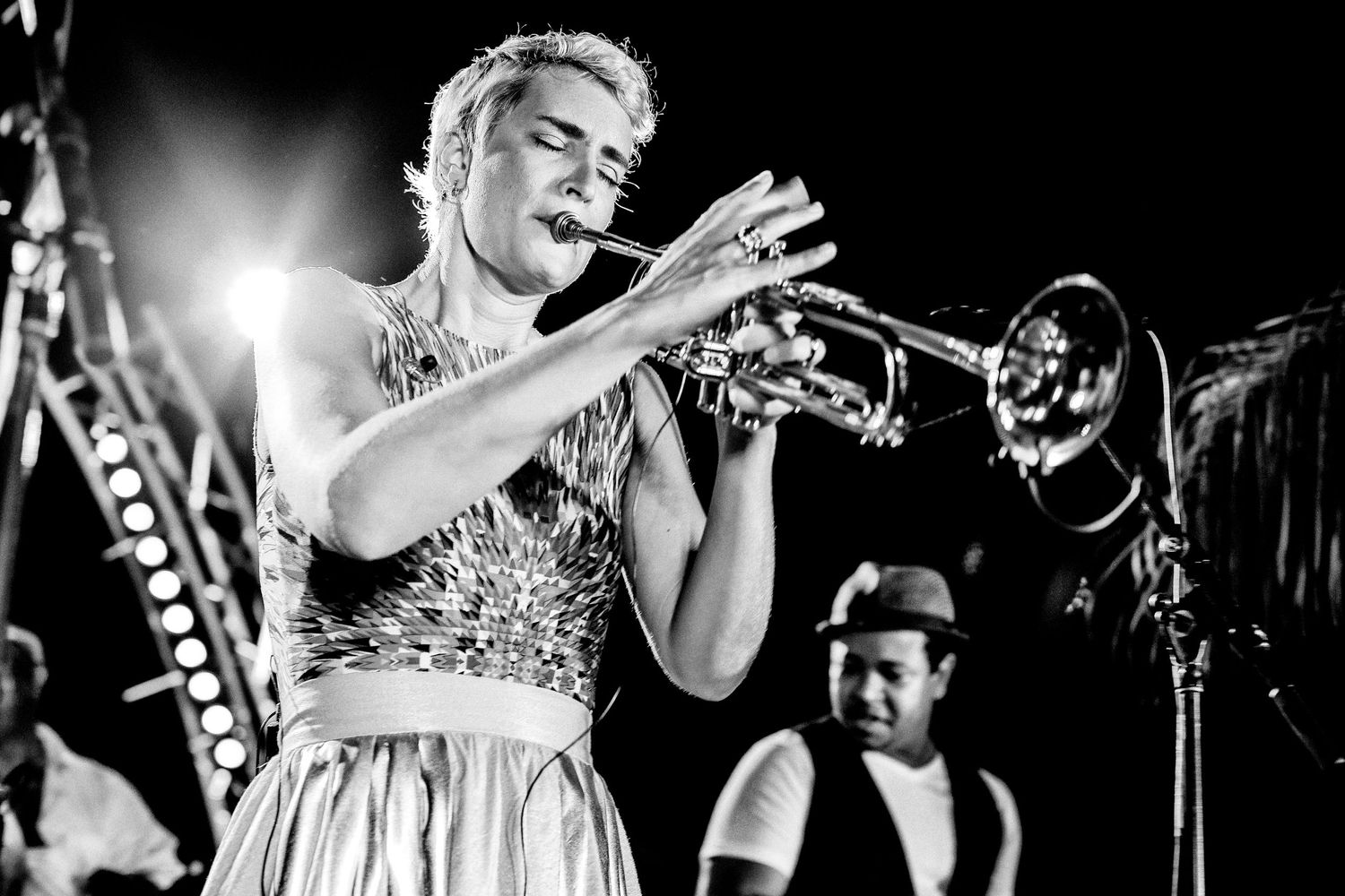 Black and white photo of a musician performing with a trumpet on stage.