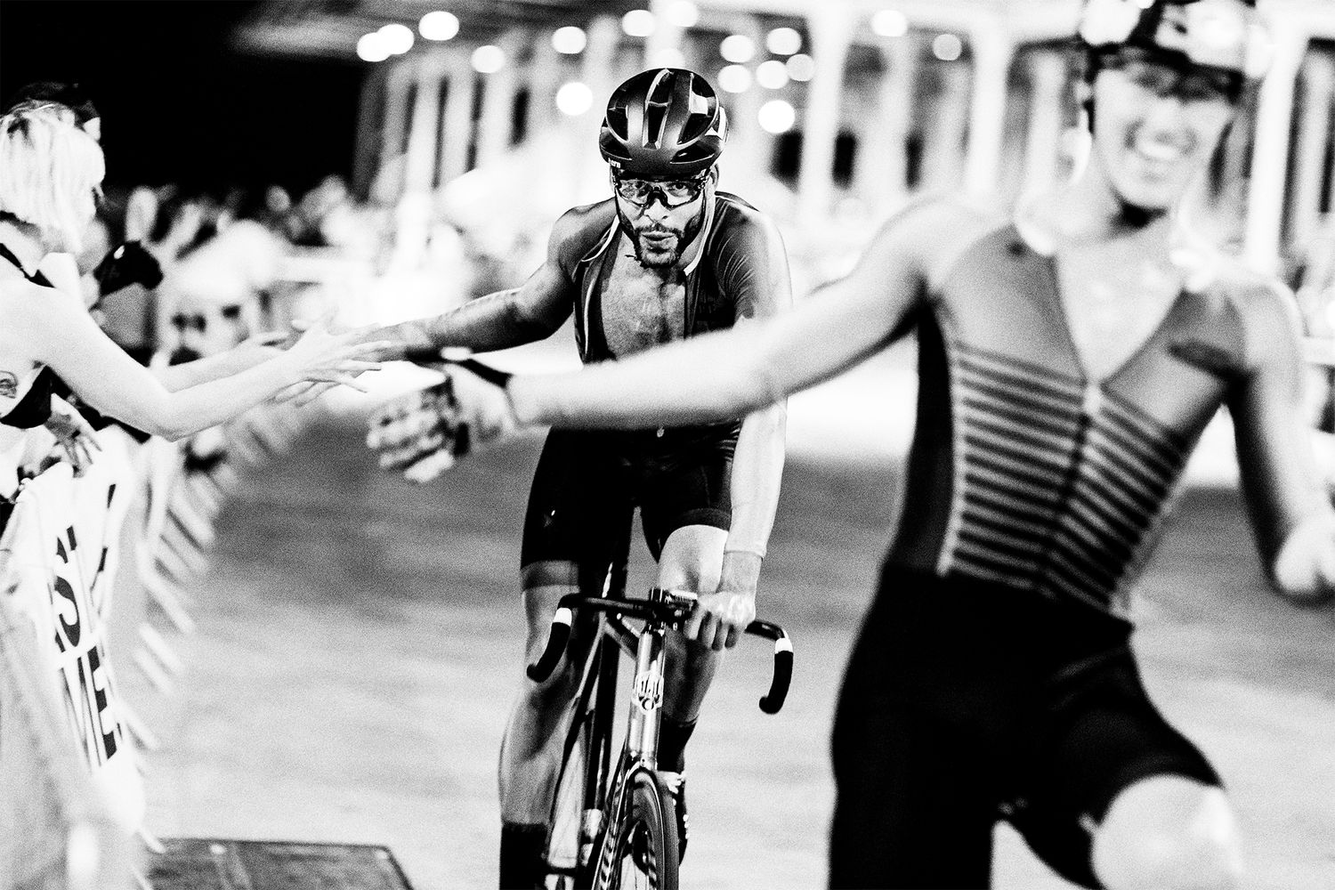Cyclist reaches out to touch hands with spectators during a race.