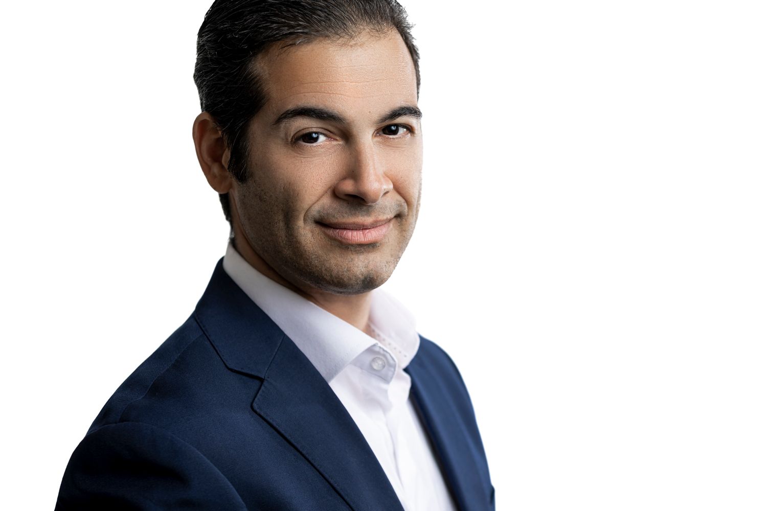 Professional headshot of someone in a navy suit jacket and white dress shirt against a white background.