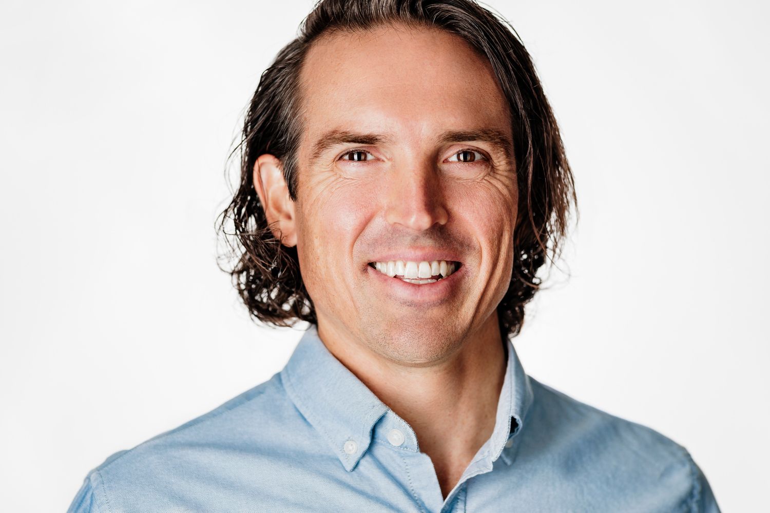 Professional headshot of a person wearing a light blue button-down shirt against a white background.