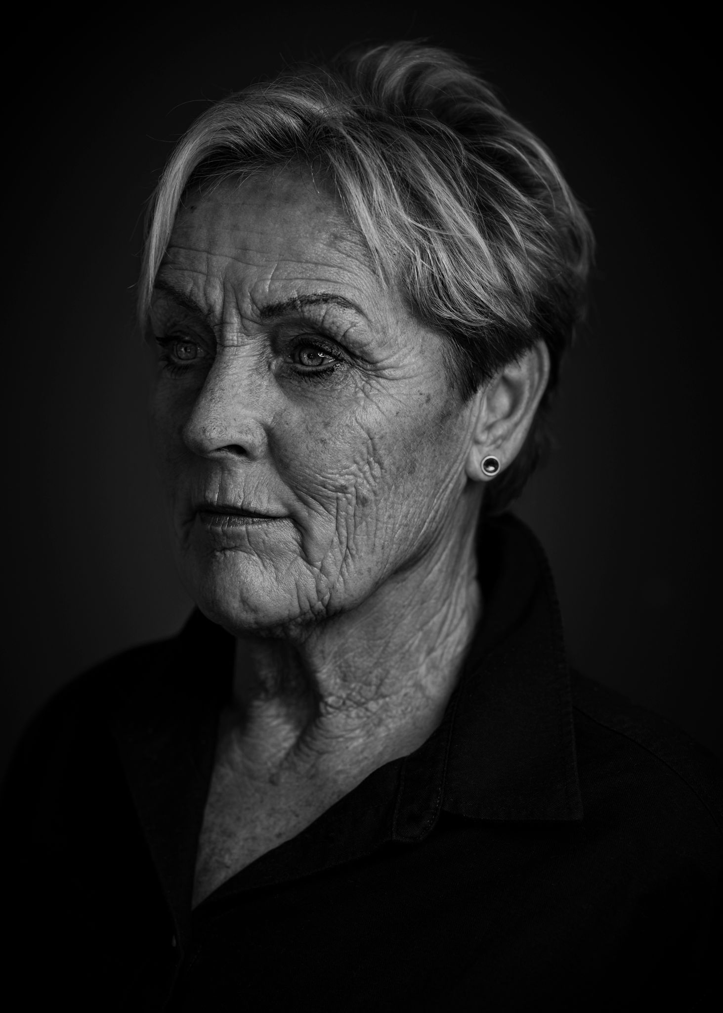 Dramatic black and white portrait showcasing texture and lighting against dark background.