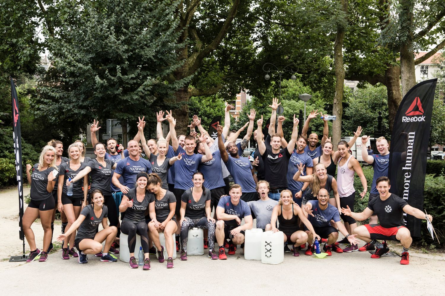 Large group celebrating with raised arms at outdoor fitness event.