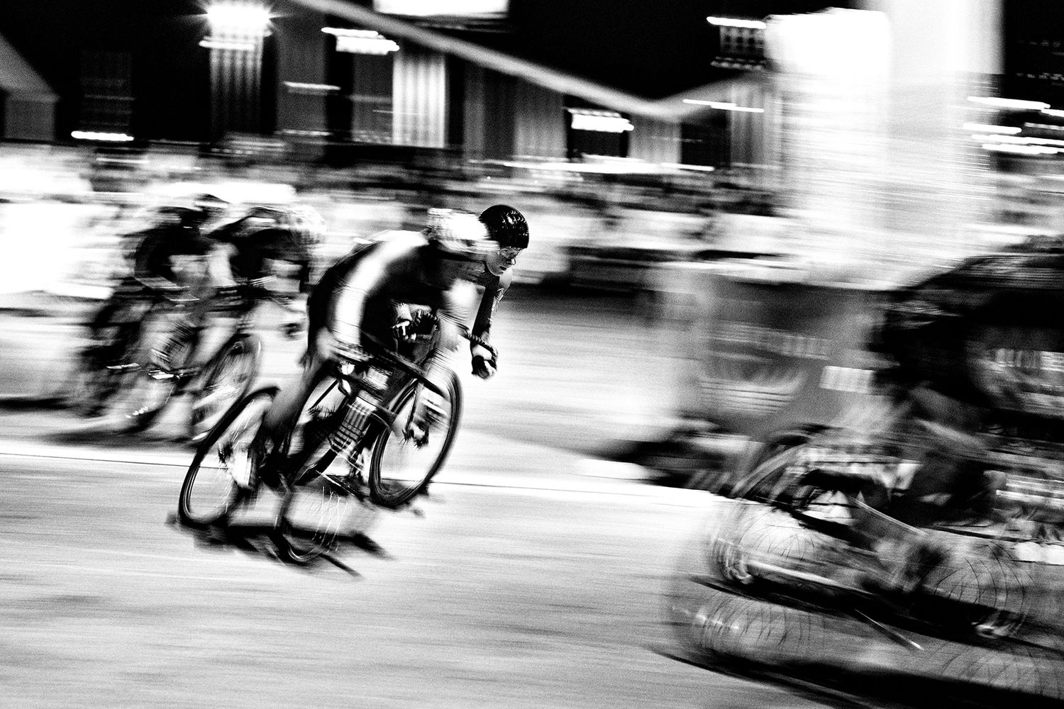 Motion blur capture of cyclists racing at high speed in black and white.