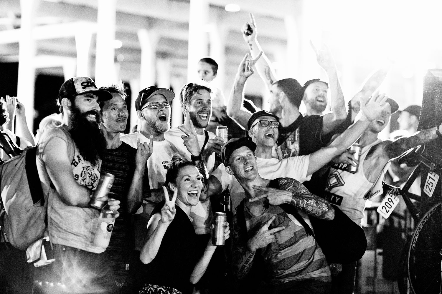 Energetic crowd celebrates at a nighttime event with raised hands and bottles.