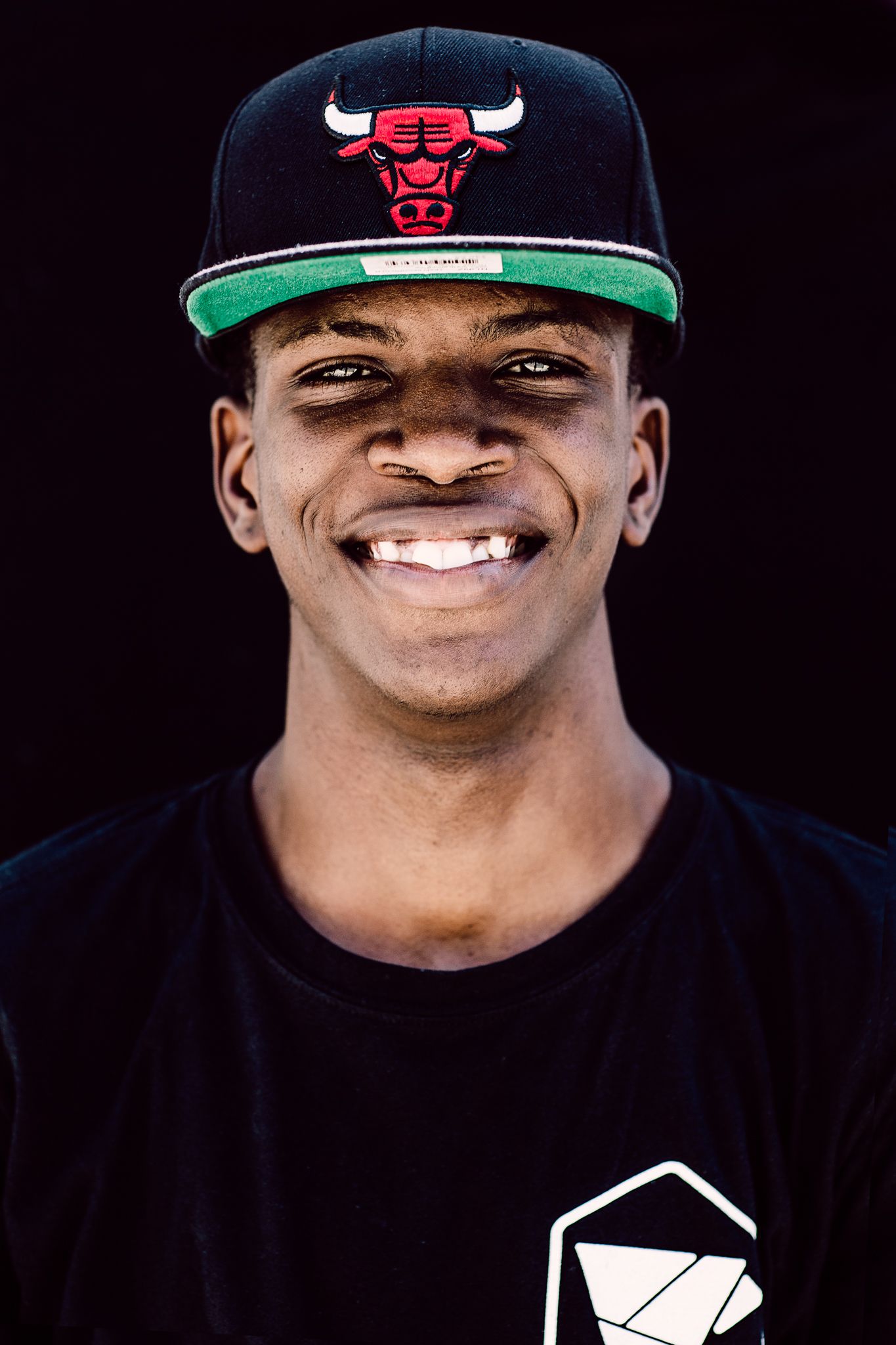 Portrait of a person wearing a Chicago Bulls cap against a black background.