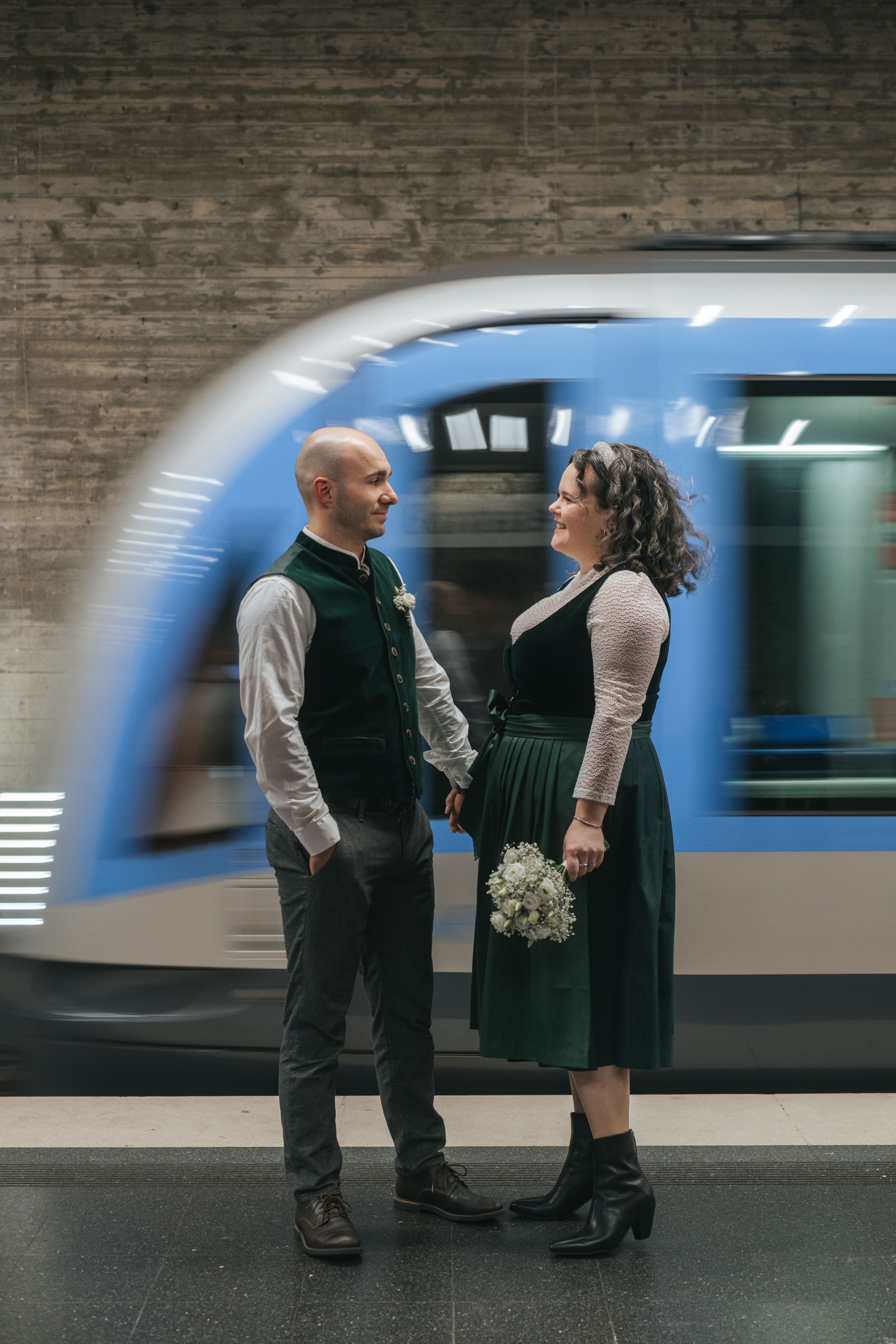 Hochzeitsfotografie: Brautpaar steht sich in einer U-Bahn-Station gegenüber, moderner Moment im urbanen Raum, in der Münchner Innenstadt.