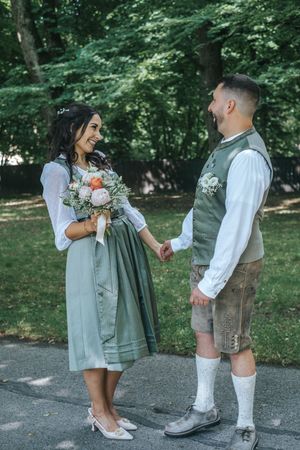 Hochzeitsfotografie: Brautpaar in Tracht, nach ihrem First Look, steht sich im Grünen gegenüber und hält sich an den Händen, fotografiert.