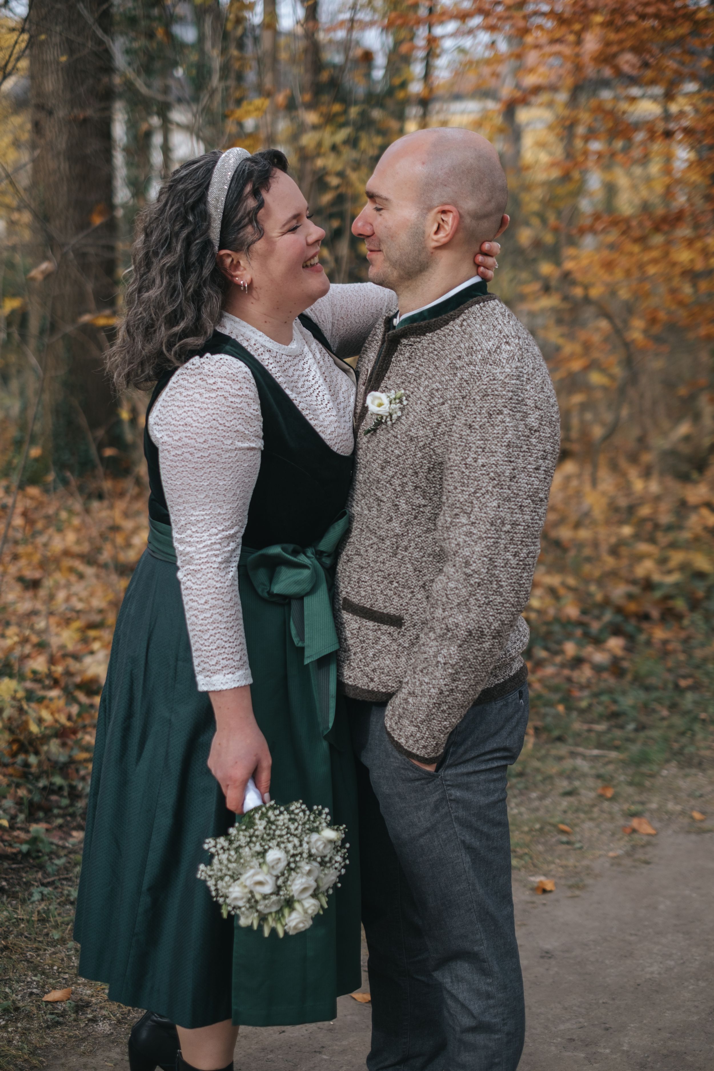 Hochzeitsfotografie Bayern: Brautpaar steht sich auf einem Weg im herbstlichen Wald gegenüber und blickt sich ruhig an.
