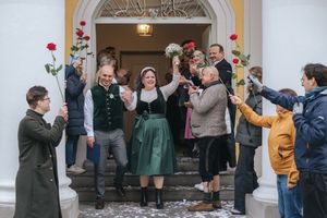 Hochzeitsfotografie: Brautpaar wird nach der Trauung von Gästen vor dem Standesamt in der Mandlstraße, in München, lebendig empfangen.