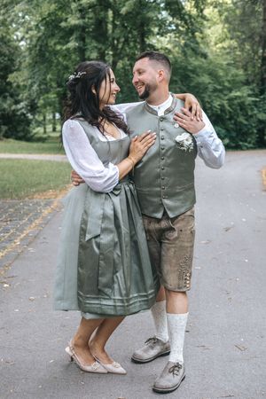 Hochzeitsfotografie: Paar in Tracht, nach dem Ismaninger Standesamt, geht gemeinsam einen Weg entlang und blickt sich an.