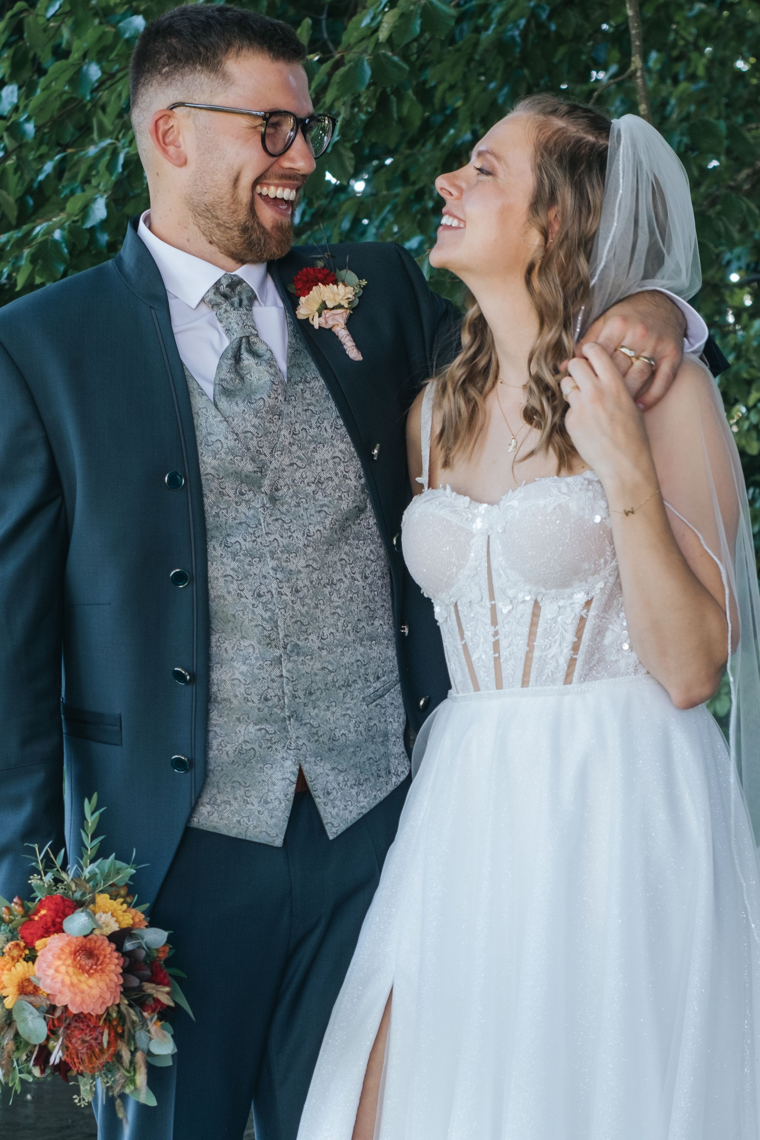 Hochzeitsfotografie in Pfaffenhofen a.d. Ilm: Brautpaar steht eng beieinander im Grünen, die Braut trägt ein trägerloses Kleid und Schleier.