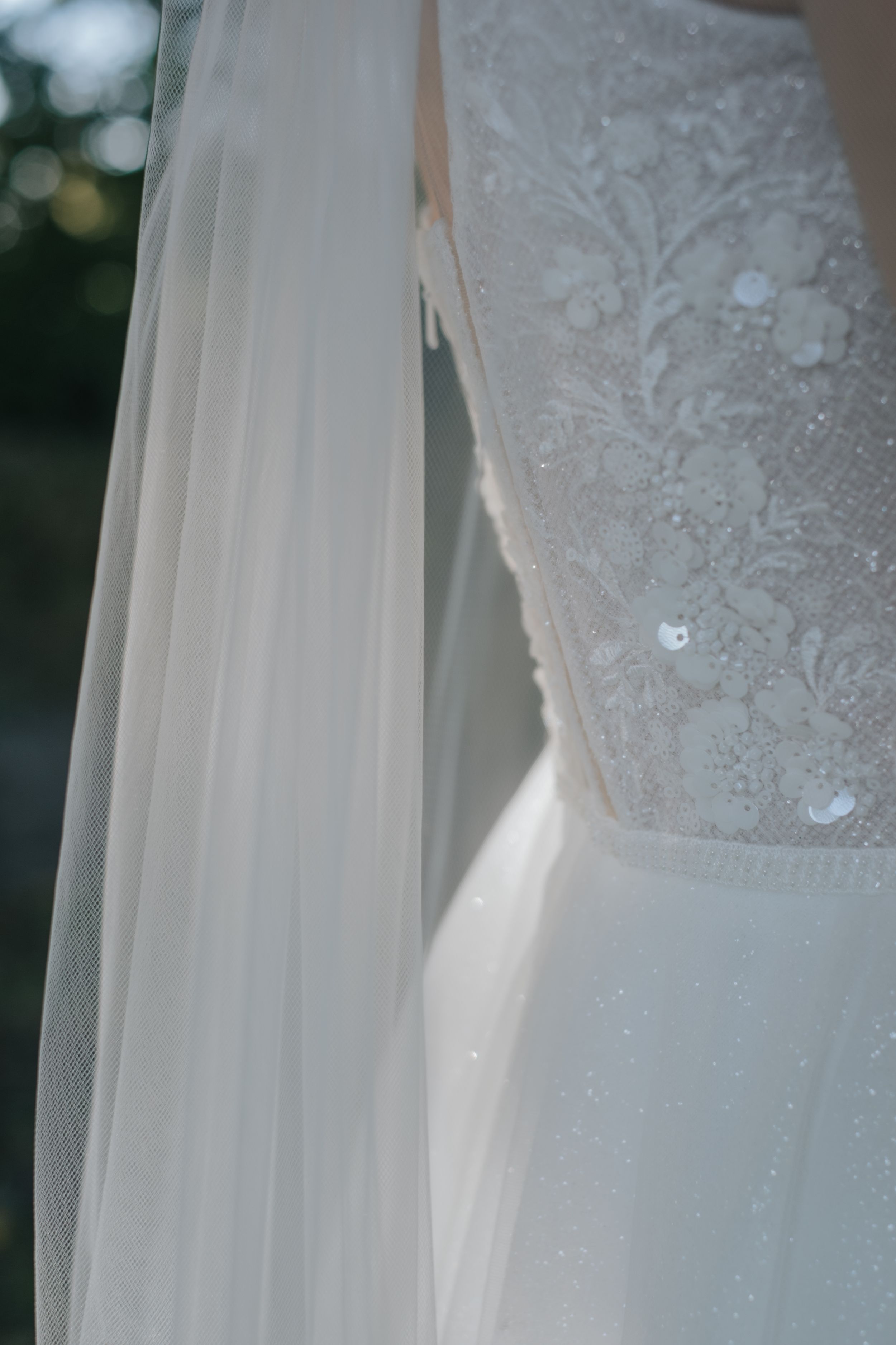 Hochzeitsfotografie in München: Detailaufnahme eines Brautkleids mit Spitze und Schleier im natürlichen Licht.“