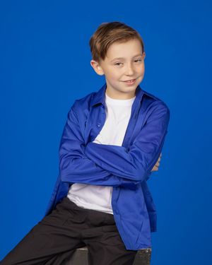 Young student in a bright blue blazer poses against a vibrant blue background.