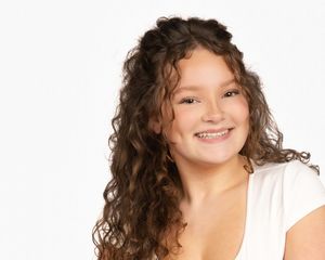 A series of four headshots showing someone with curly brown hair and a bright smile against a white background.