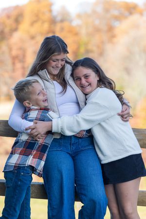 A loving family moment captured outdoors with warm embraces and laughter against an autumn backdrop.