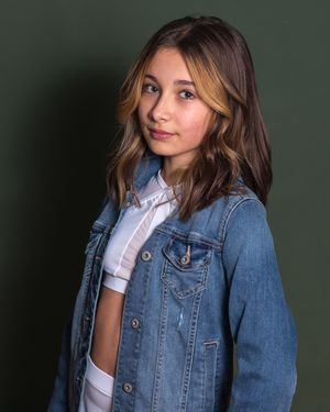 A woman in a denim jacket and white top poses against a dark background in a series of fashion portraits.
