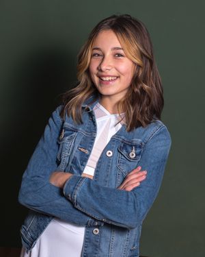 A person in a denim jacket and white shirt poses against a dark background with various expressions and poses.