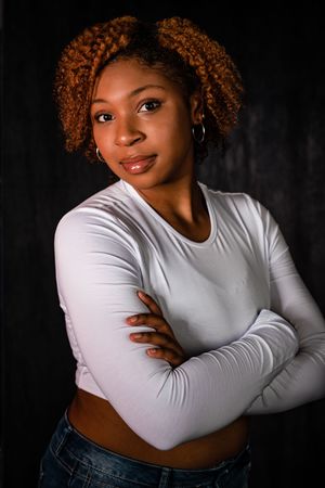 Portrait series of a person in a white long sleeve top and jeans against a dark background.
