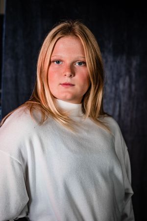 A series of moody portrait shots showing someone wearing a white sweater against a dark background.
