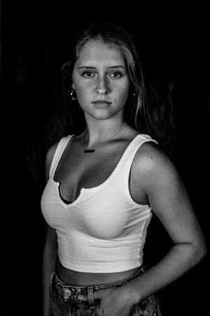 Dramatic black and white portrait series showing a person in a white tank top and denim against dark background.