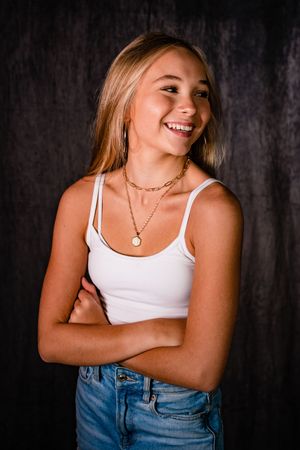 Portrait series showing person in white tank top and jeans against dark background with natural expressions and poses.
