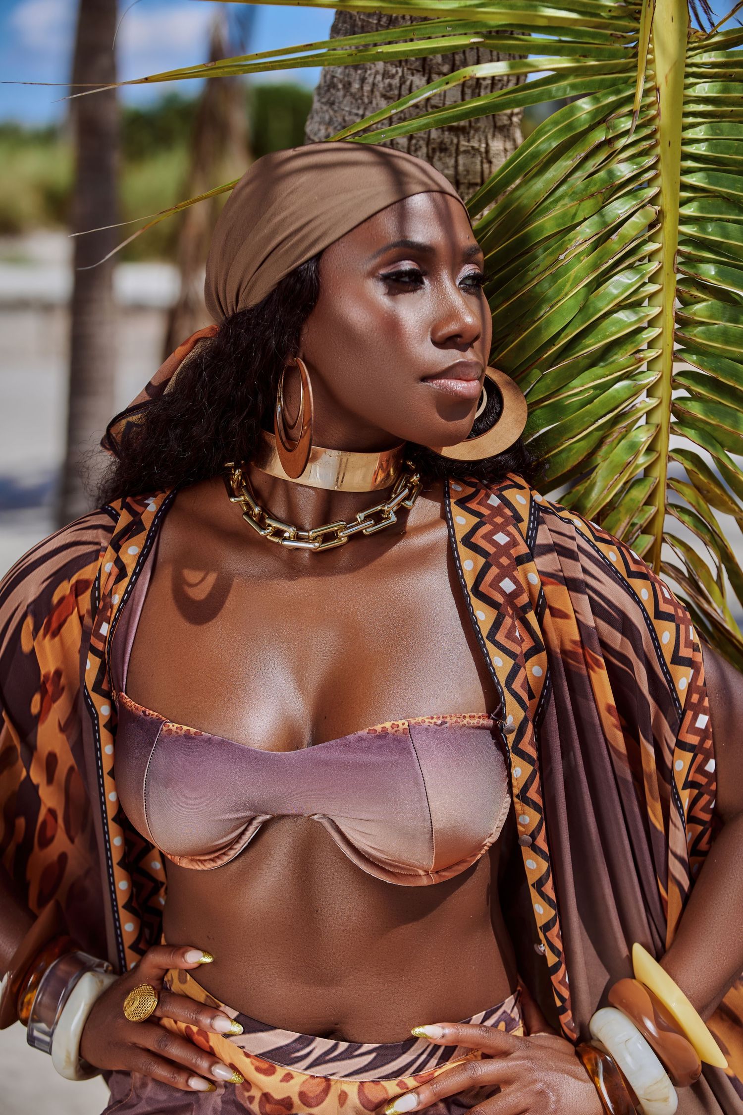 Close-up of a fashionable woman wearing sunglasses and a brown swimsuit, basking in the tropical sun