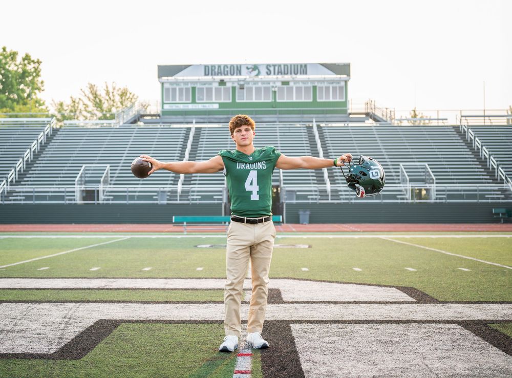 Senior portrait session at high school football stadium featuring green and white team colors.