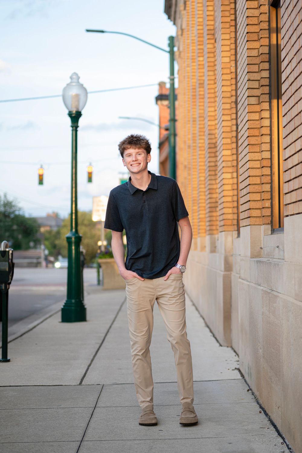 Casual outdoor portraits along a brick building with vintage street lamps.