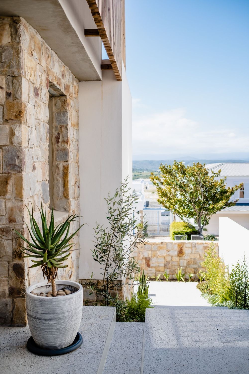 Modern Mediterranean villa exterior with potted plants and scenic landscape view.
